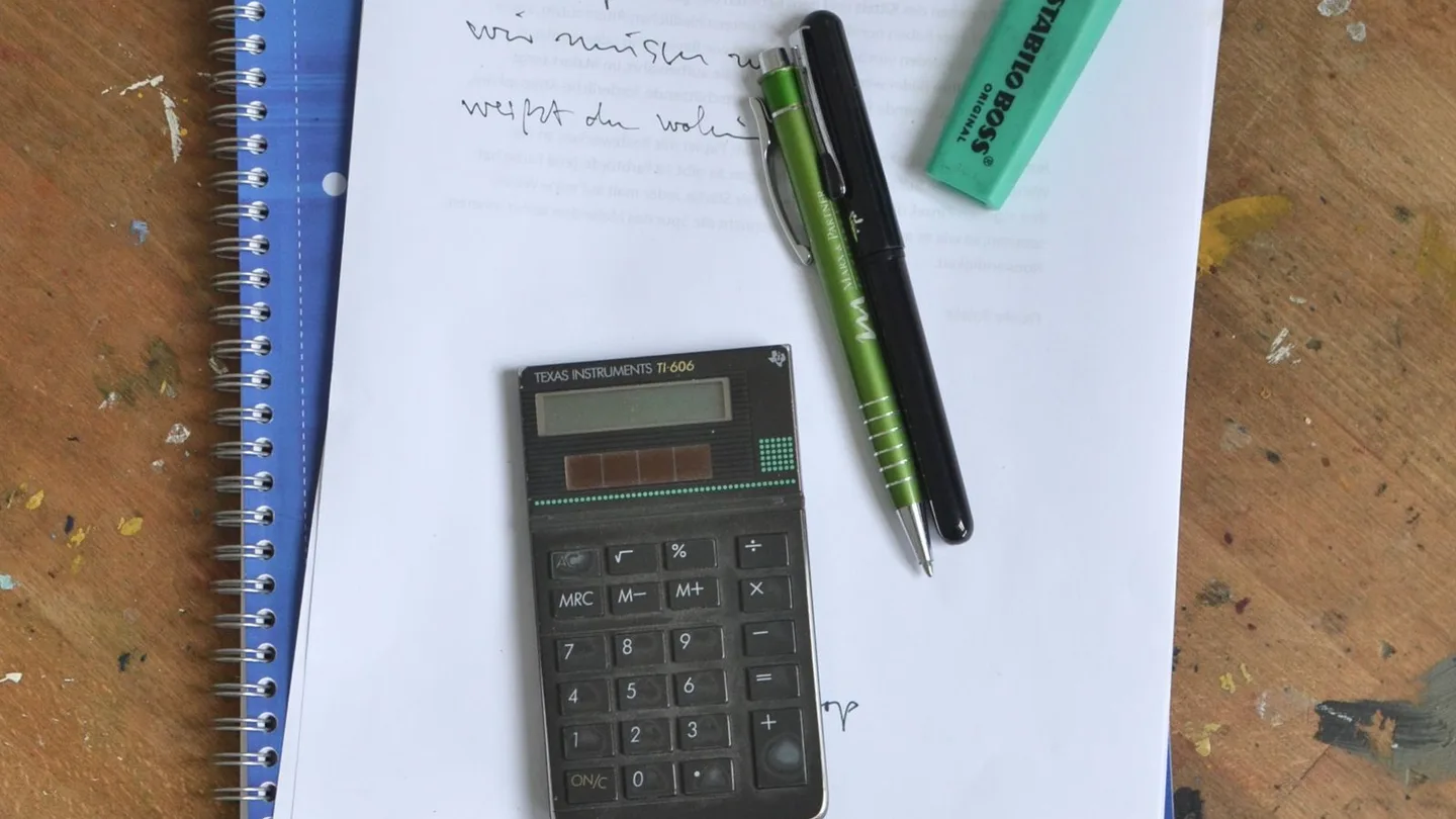 Quaderno, fogli di calcolo e calcolatrice su una scrivania